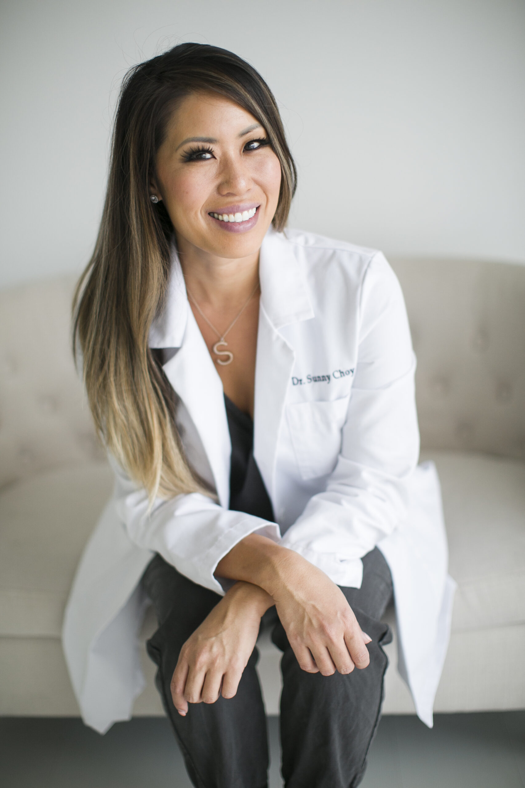 Dr. Sunny Choy, seated, wearing a white coat embroidered with her name